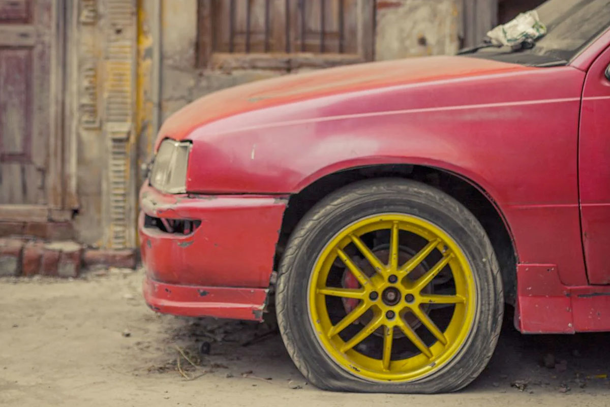 Close-up of a red car's front wheel with yellow rims.